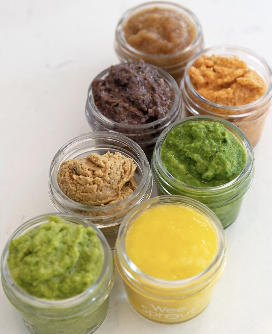 Small jars of colorful homemade purées on a white counter