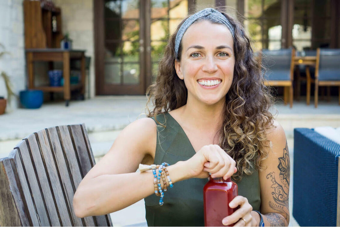Carly Brown smiling and holding a bottle of red juice