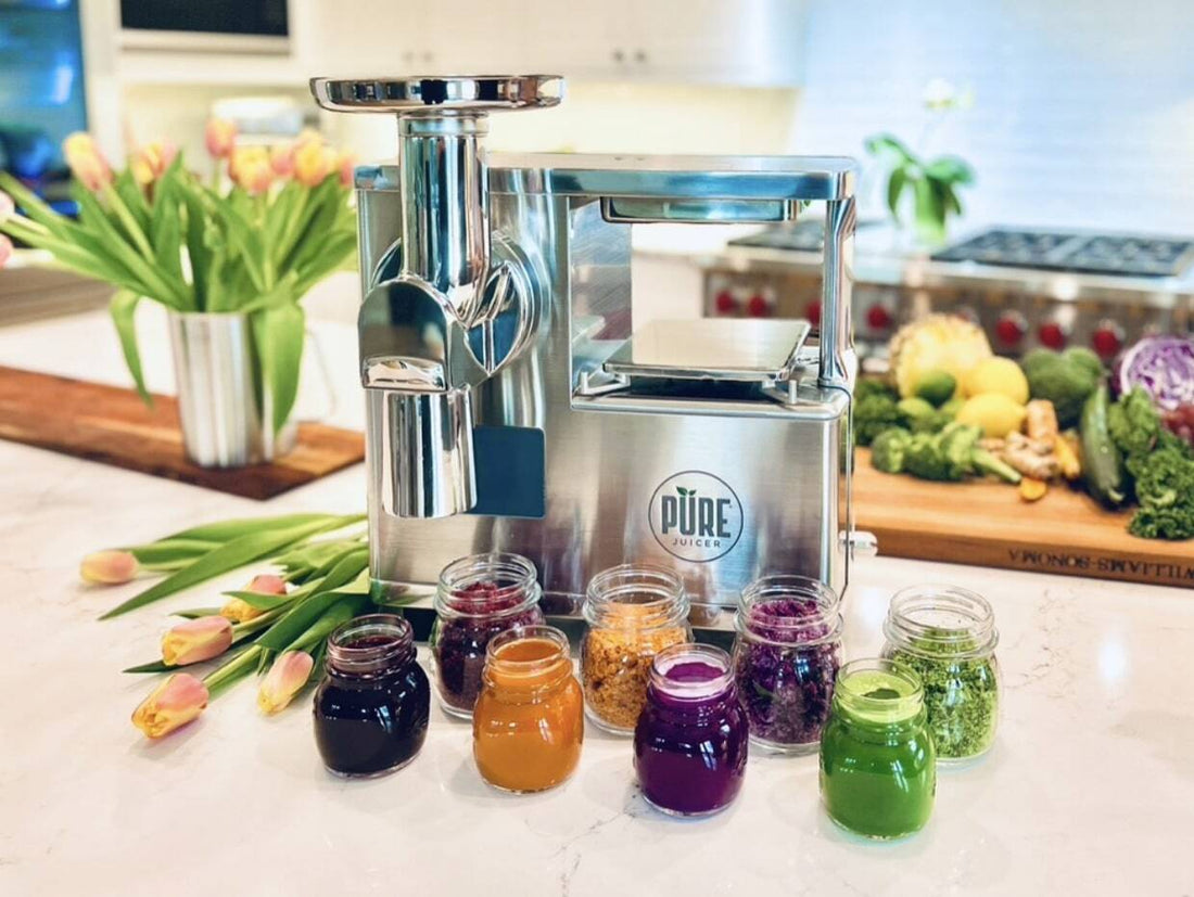 Jars of colorful juice pulp and produce around the PURE Juicer