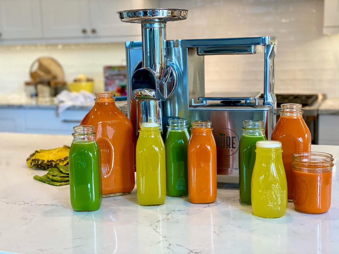 A rainbow of juice bottles lined up in front of a juicer