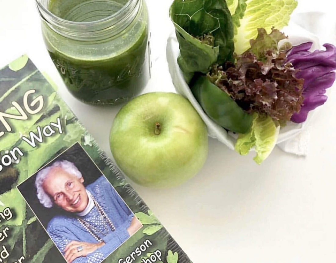 Green juice, green apples and leafy greens beside a Gerson juicing book