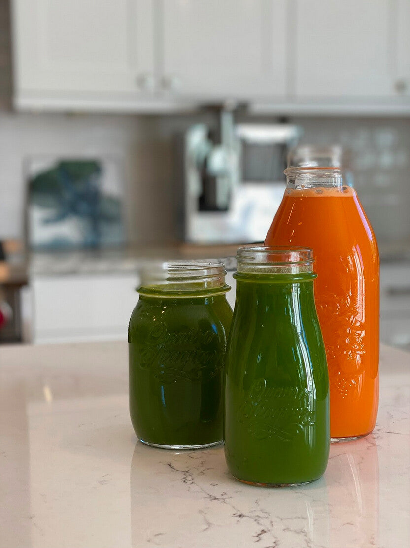 Bottles of green and orange juice on a kitchen counter