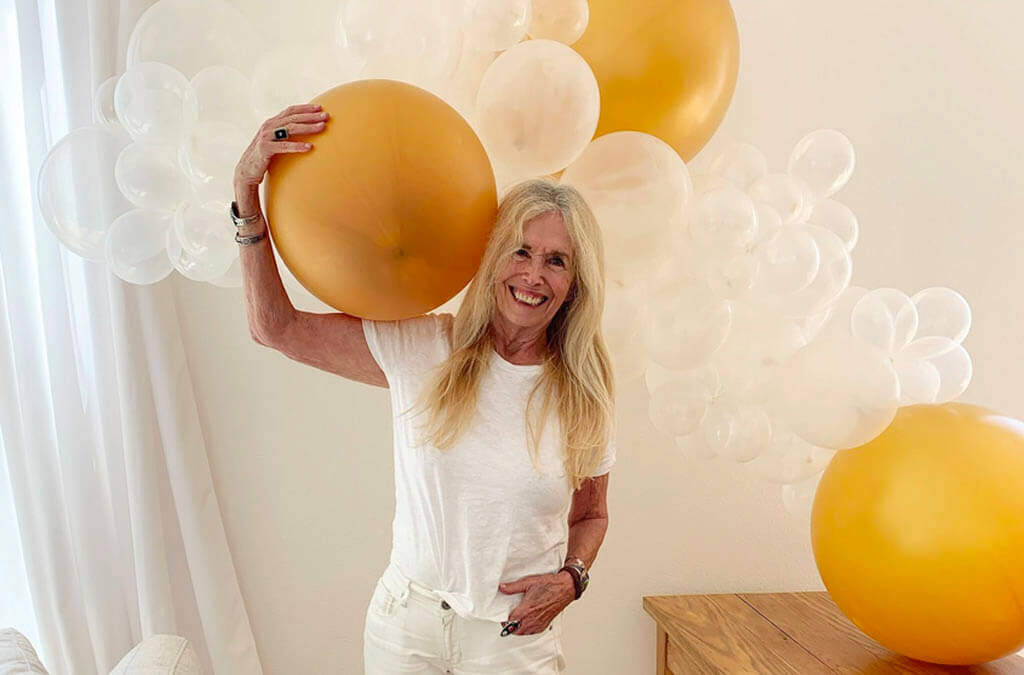 Mimi Kirk smiling, holding a gold balloon