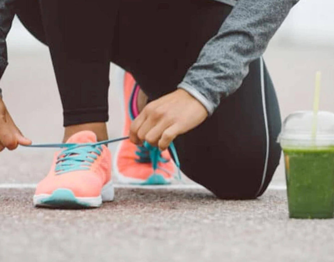 Runner tying a shoe next to a cup of green juice