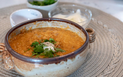 A bowl of orange soup garnished with fresh herbs and a dollop of cream