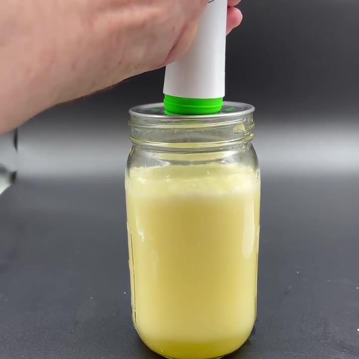 Juice in a lidded mason jar foaming as the pump draws the vacuum
